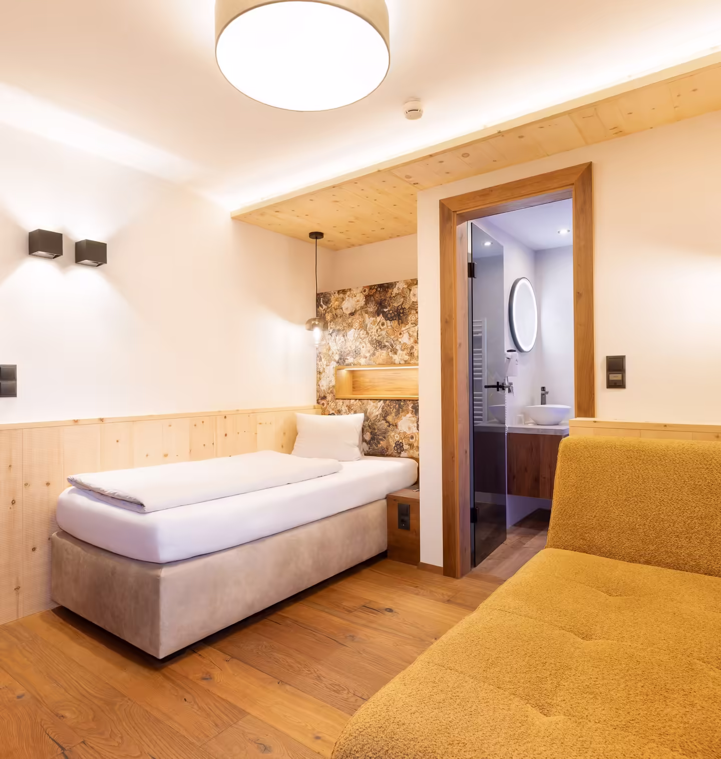 Zimmer mit Einzelbett und gelber Couch in moderner Einrichtung